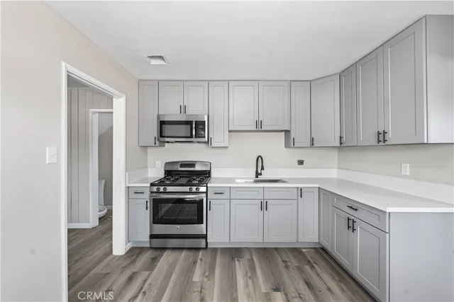 a kitchen with cabinets stainless steel appliances a sink and wooden floor
