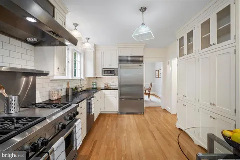 a kitchen with granite countertop a refrigerator a stove and wooden floor