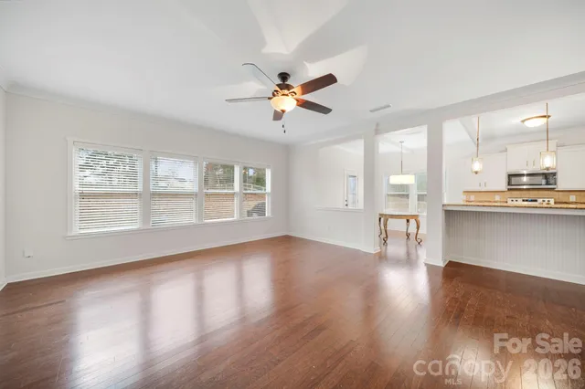 a view of an empty room with window and wooden floor