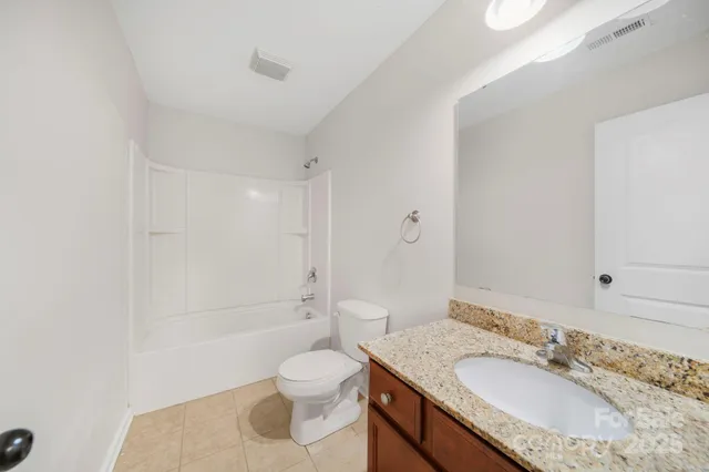 a bathroom with a granite countertop sink a toilet and shower