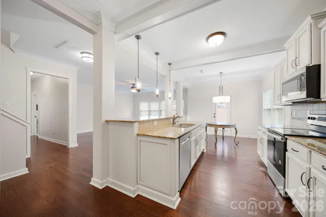 a kitchen with granite countertop a stove top oven a sink dishwasher and a refrigerator with wooden floor