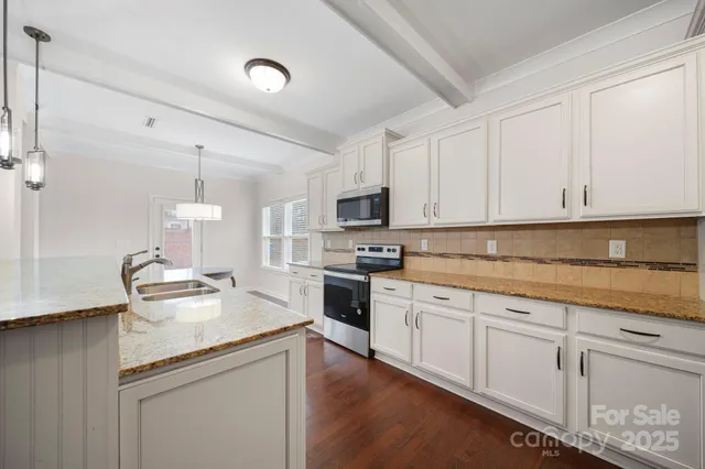 a kitchen with kitchen island granite countertop a sink stainless steel appliances and white cabinets