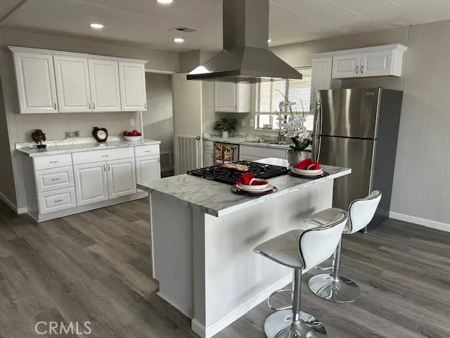 a kitchen with stainless steel appliances granite countertop a refrigerator a sink dishwasher a stove and white cabinets with wooden floor