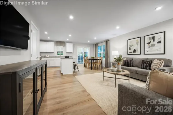 a living room with stainless steel appliances furniture a flat screen tv and kitchen view