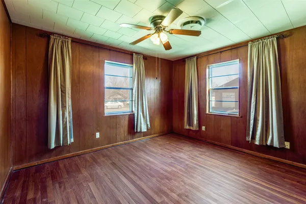 an empty room with windows and ceiling fan