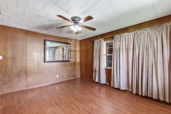 an empty room with wooden floor fan and windows