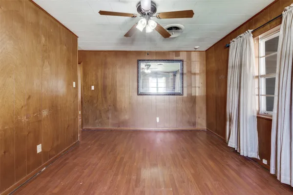 a view of empty room with wooden floor and fan