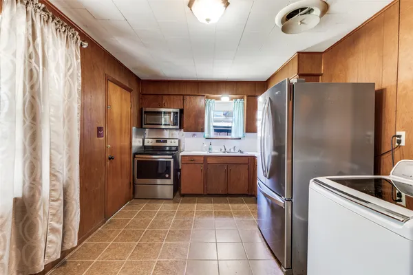 a large kitchen with stainless steel appliances granite countertop a refrigerator and a sink