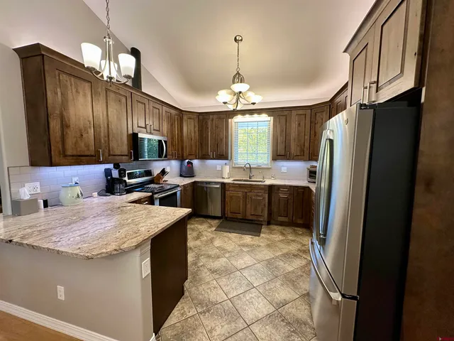 a kitchen with stainless steel appliances granite countertop a refrigerator a sink a stove and dishwasher