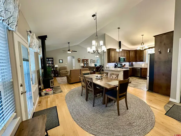 a dining room with stainless steel appliances kitchen island granite countertop a table chairs and a rug