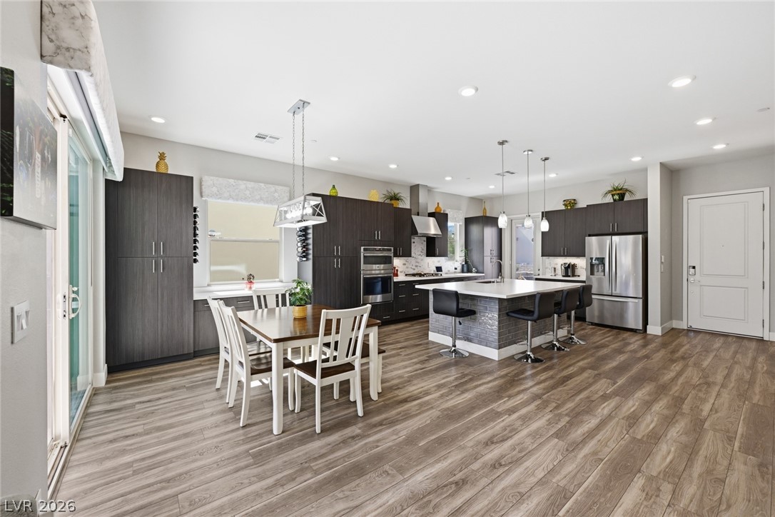 4246 Swift Street Las Vegas, NV 89135 - Photo 14 of 71 Kitchen featuring a breakfast bar area, dark wood finish cabinetry, a center island, stainless steel appliances, and light wood-style floors