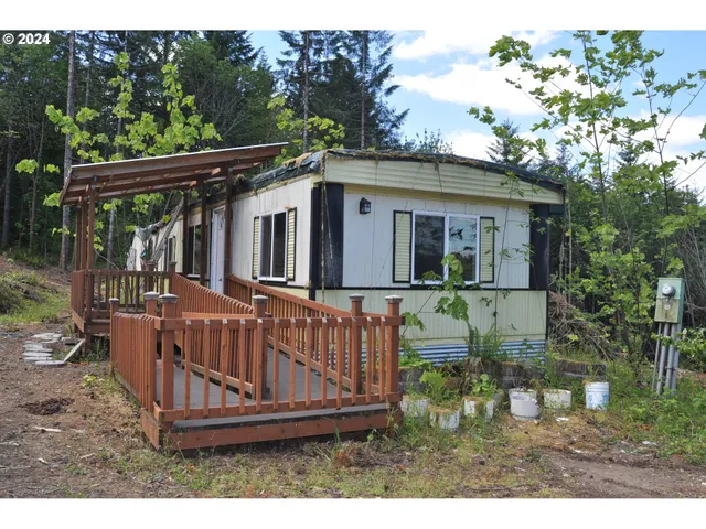 a view of a small house with wooden deck and furniture