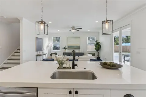 a kitchen with a sink a stove and chairs with wooden floor