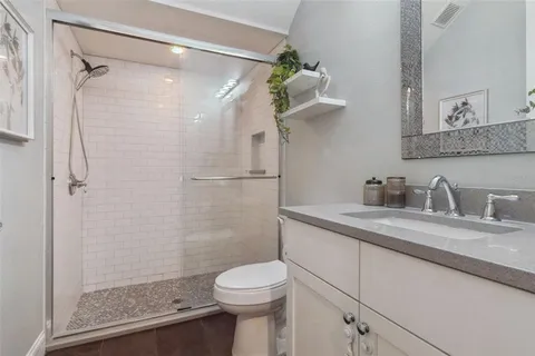 a bathroom with a granite countertop sink a toilet and shower