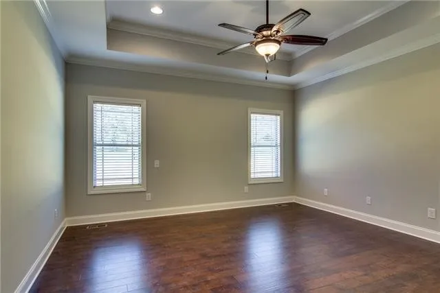 an empty room with wooden floor chandelier fan and windows