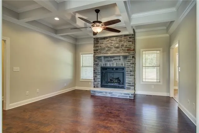 an empty room with wooden floor fireplace and windows