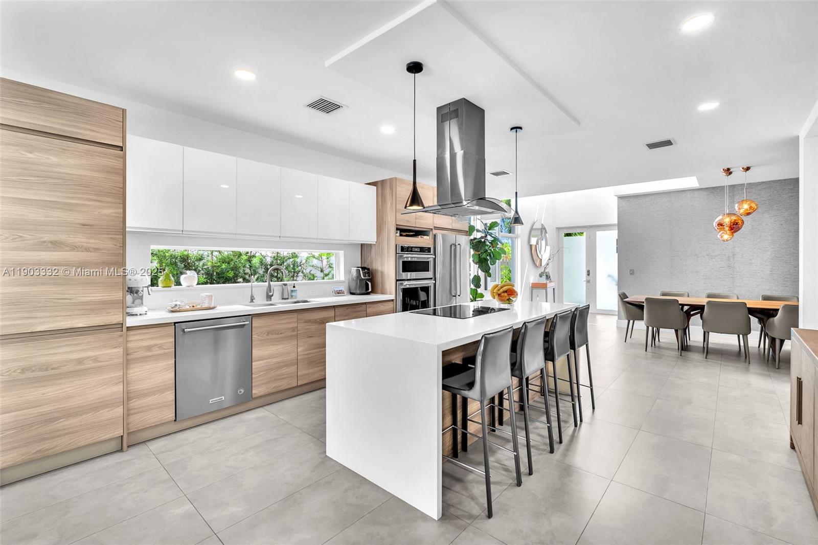 3167 Southwest 25th Street, Unit 1 Miami, FL 33133 - Photo 8 of 42 a kitchen with stainless steel appliances kitchen island granite countertop a table and chairs in it