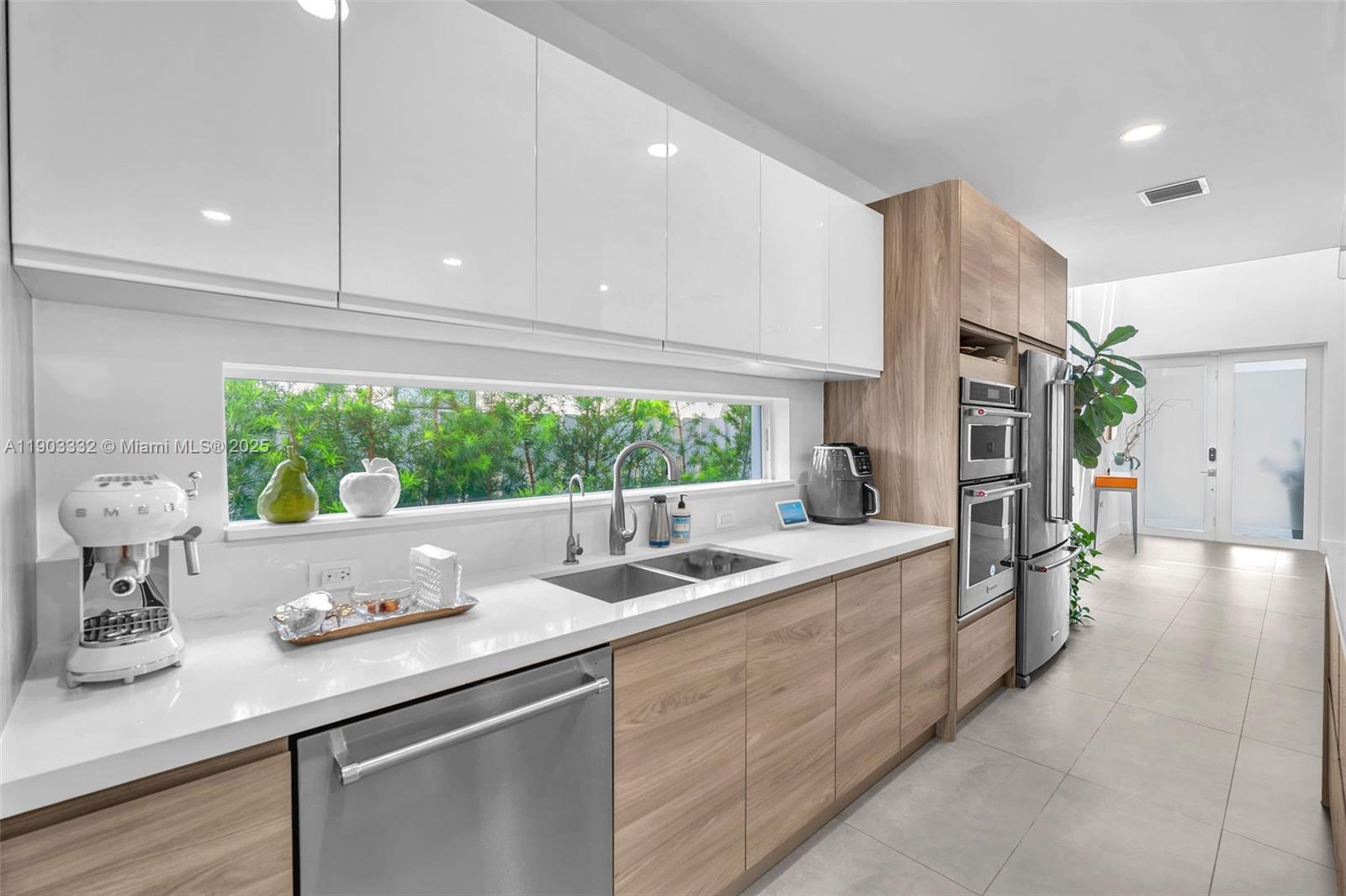 3167 Southwest 25th Street, Unit 1 Miami, FL 33133 - Photo 10 of 42 a kitchen with stainless steel appliances granite countertop a sink and a large window