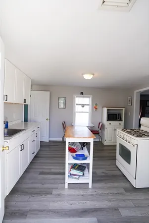 a large white kitchen with cabinets and wooden floor