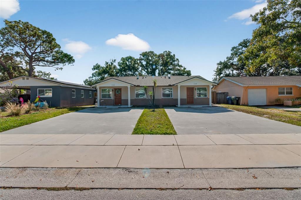 a view of house with a yard and potted plants