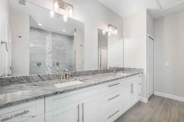 a bathroom with a granite countertop double vanity sink and mirror