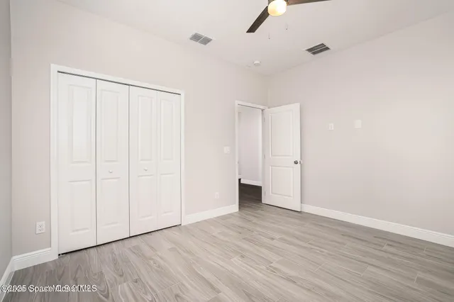 an empty room with wooden floor closet and windows