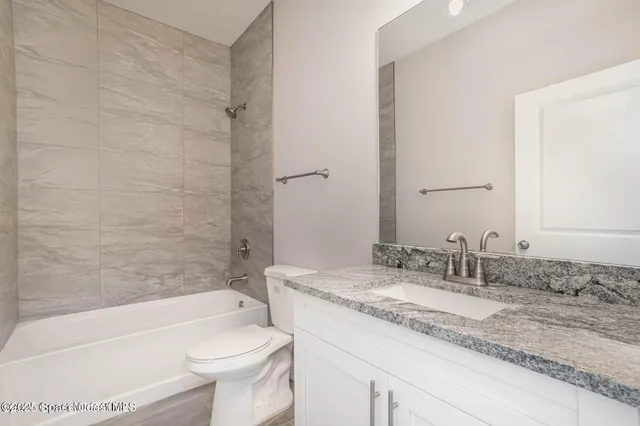 a bathroom with a granite countertop toilet a sink and bathtub