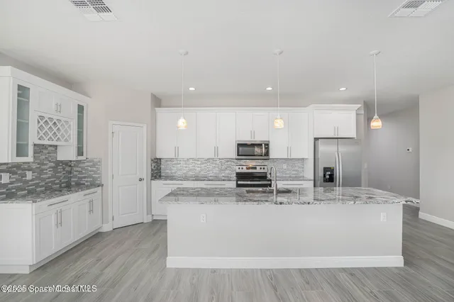 a large kitchen with stainless steel appliances kitchen island a large counter top and a stove