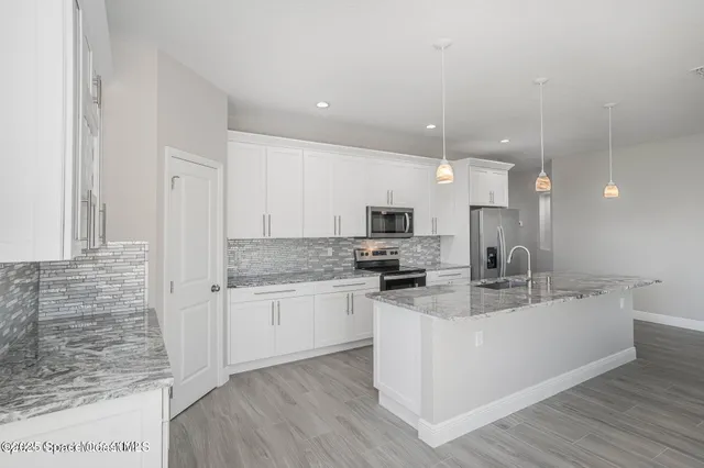 a kitchen with stainless steel appliances kitchen island granite countertop a stove a sink and a refrigerator