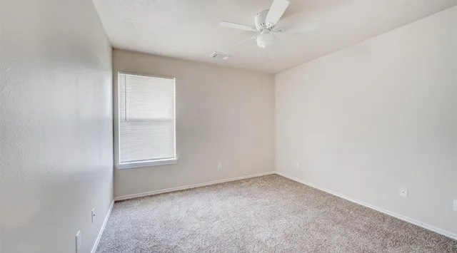 an empty room with a ceiling fan and window