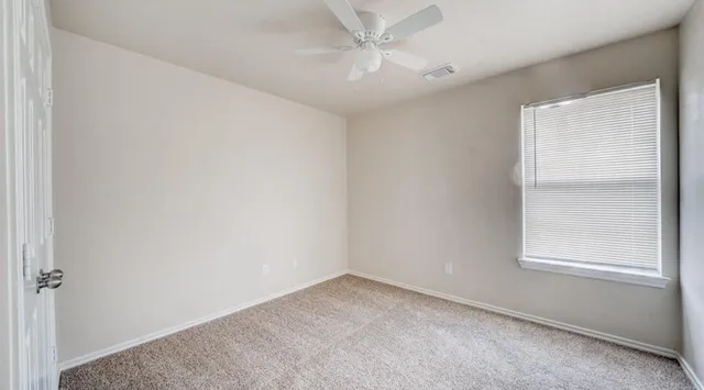 an empty room with a window and a fan