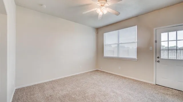 an empty room with windows and chandelier fan