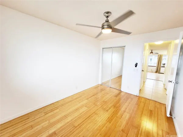a view of a room with wooden floor and ceiling fan