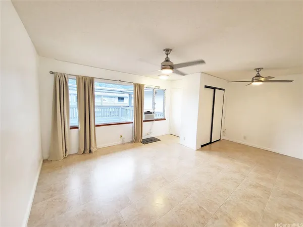 an empty room with chandelier fan and windows