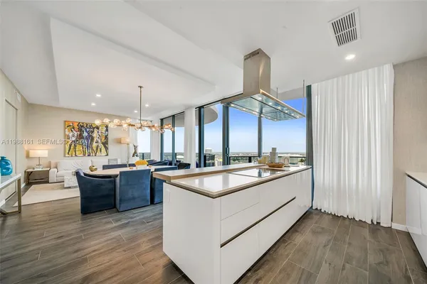 a large kitchen with kitchen island a large counter space a sink appliances and wooden floor