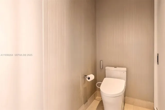a white toilet sitting next to a white wall