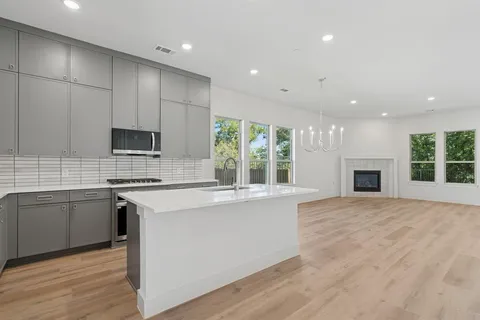 a kitchen with stainless steel appliances granite countertop a stove top oven a sink dishwasher and a refrigerator with wooden floor