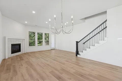 a view of an empty room with wooden floor fireplace and a window