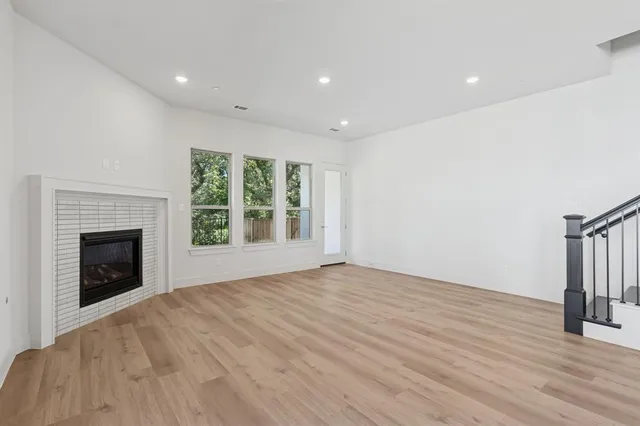 a view of an empty room with wooden floor fireplace and a window