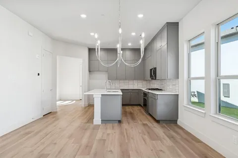 a large kitchen with a sink and wooden floor