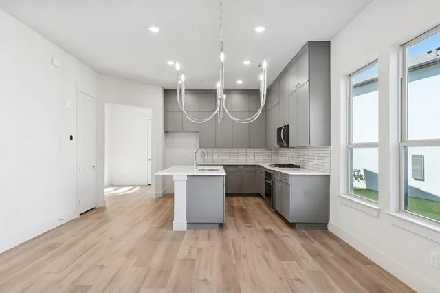 a large kitchen with a sink and wooden floor