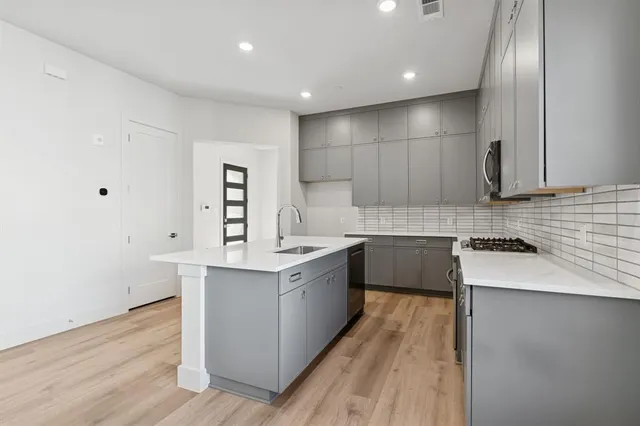 a large kitchen with a lot of counter space and wooden floor