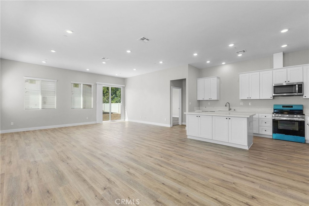 1341 East 8th Street Beaumont, CA 92223 - Photo 17 of 38 a view of kitchen with granite countertop refrigerator oven sink and white cabinets with wooden floor