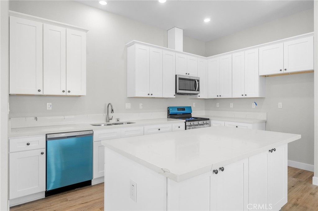 1341 East 8th Street Beaumont, CA 92223 - Photo 21 of 38 a kitchen with stainless steel appliances white cabinets and a sink