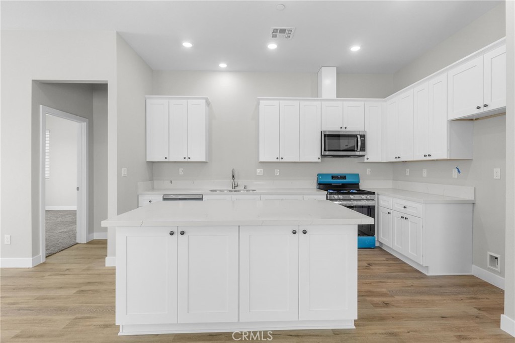 1341 East 8th Street Beaumont, CA 92223 - Photo 22 of 38 a kitchen with kitchen island granite countertop a sink a stove a refrigerator and white cabinets