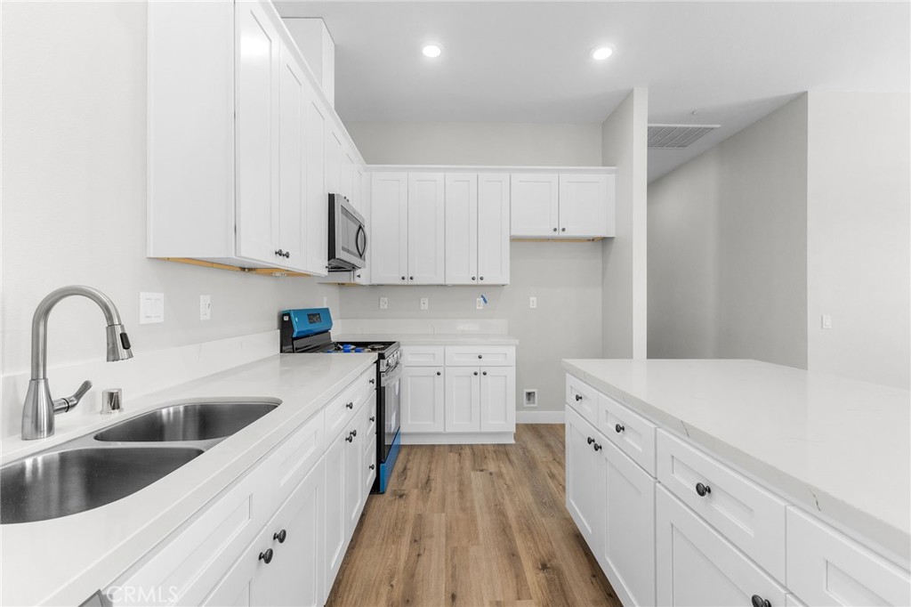 1341 East 8th Street Beaumont, CA 92223 - Photo 23 of 38 a kitchen with white cabinets sink and stove