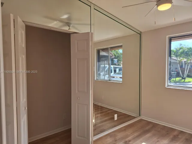 a view of empty room with wooden floor and fan