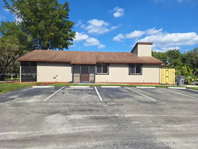 a view of a white house with a yard and palm trees