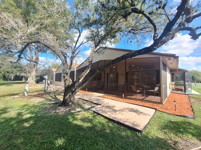 an aerial view of a residential houses with outdoor space and trees