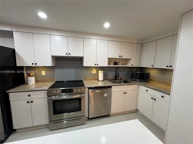 a kitchen with granite countertop white cabinets and stainless steel appliances